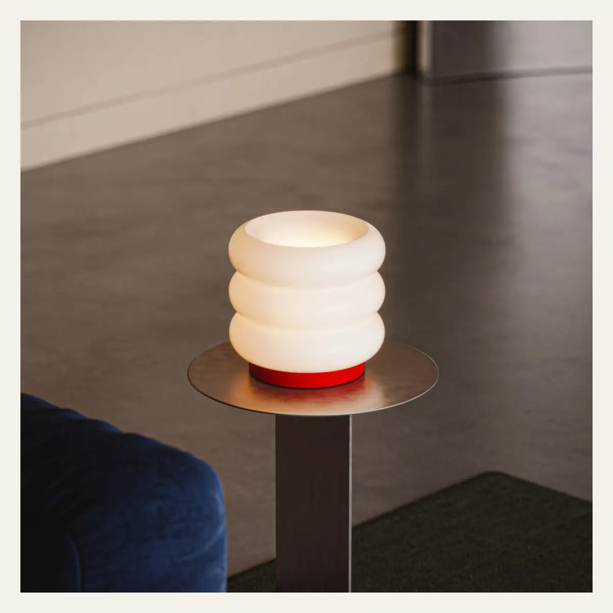 A ribbed glass lamp glowing on a slim side table.