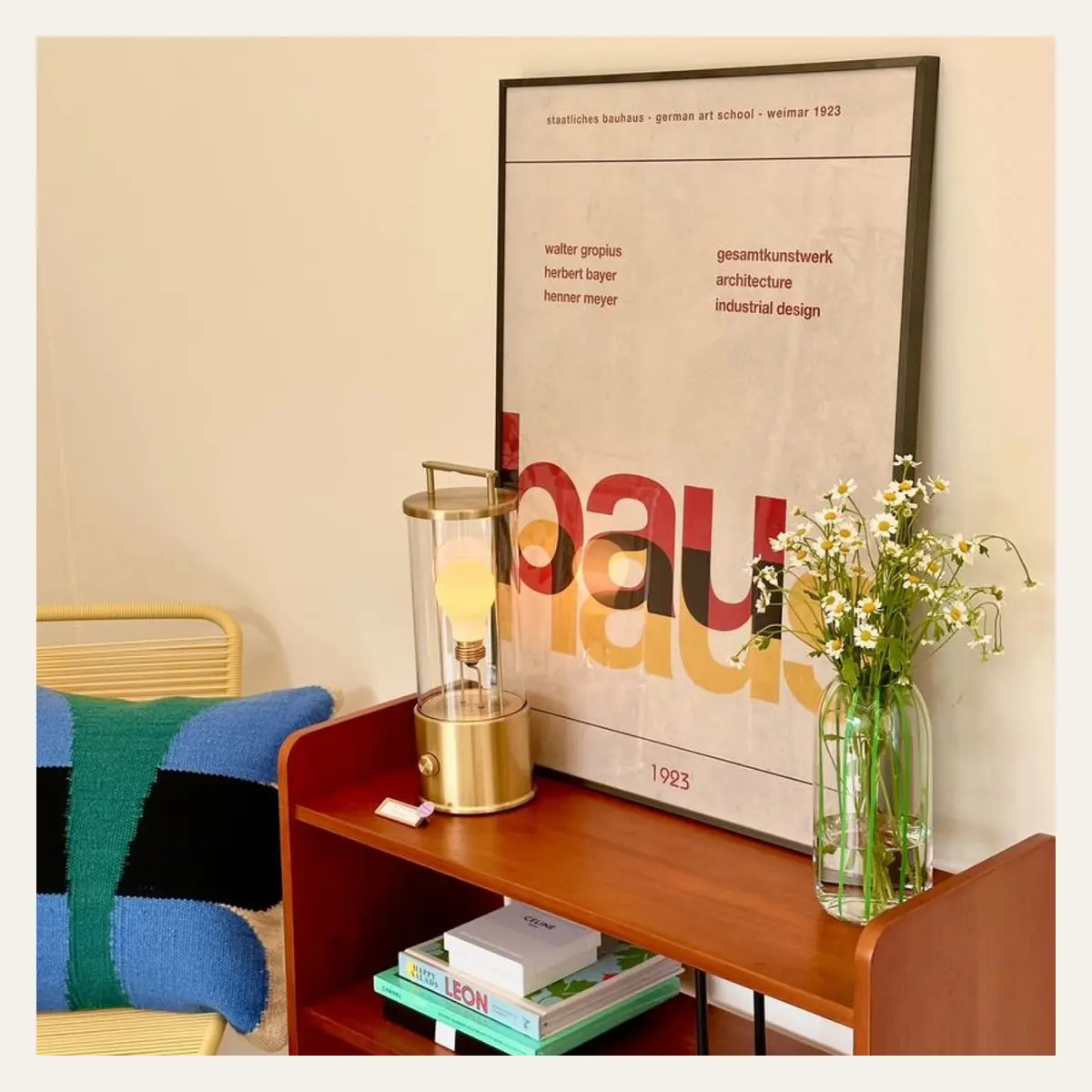 A brass portable lamp styled on a red sideboard.